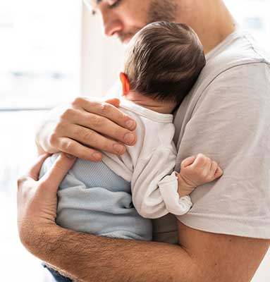 man cuddling sleeping baby.