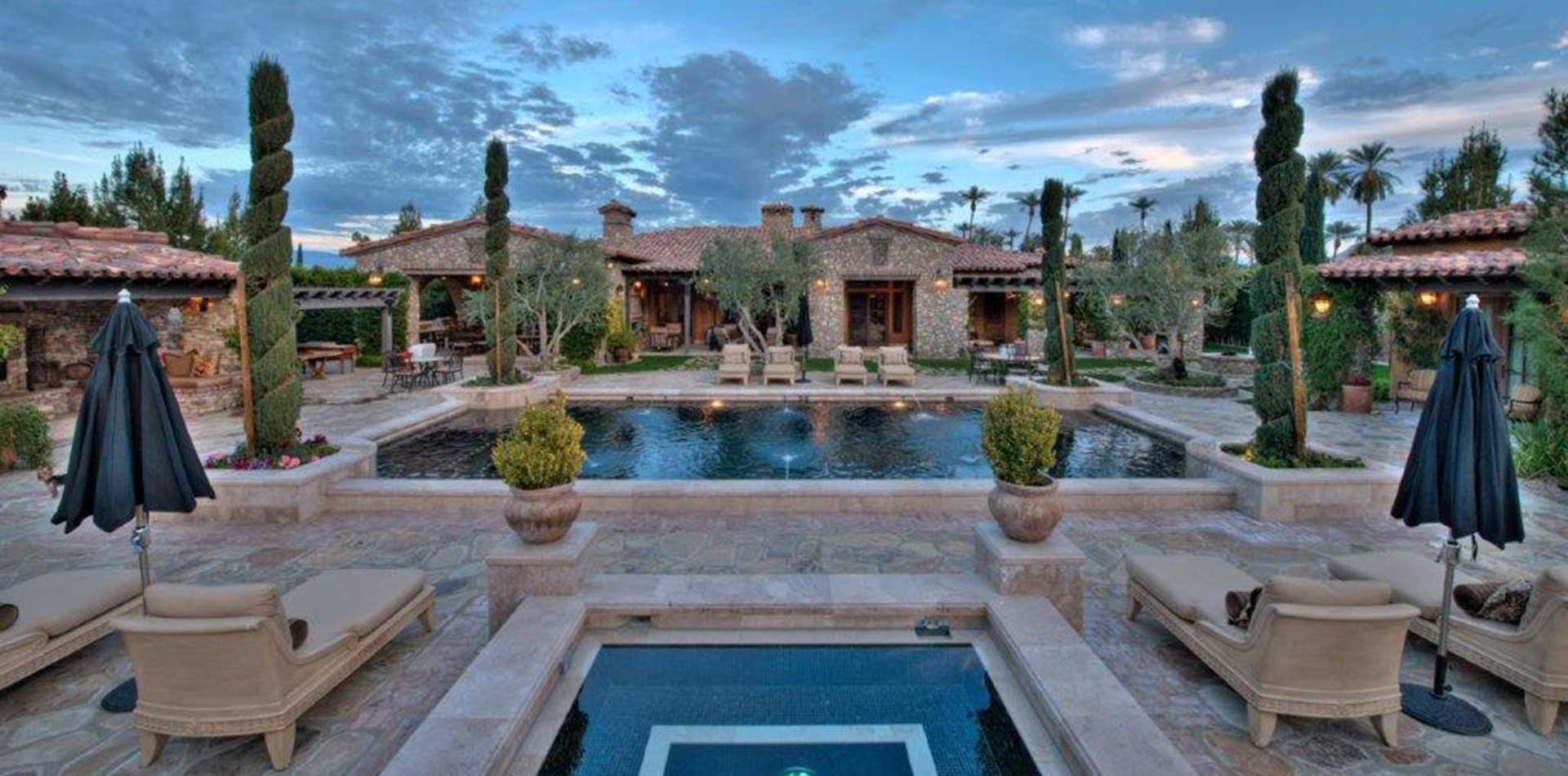 rear yard of model home at dusk with pool and spa.